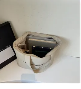 Detail view of large cream tote bag with books and tablet showing high storage capacity