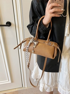 Brown cylinder Boston handbag with silver bow charm and black-white braided tassels
