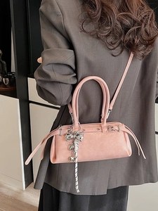 Pink Boston handbag with bow charm shown on model in a stylish crossbody wear