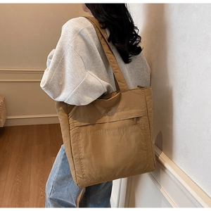 Detailed macro view of khaki canvas tote bag with functional front pocket on a model