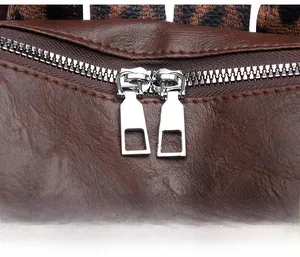Detail shot of dual silver metal zippers and high-quality brown lychee leather stitching