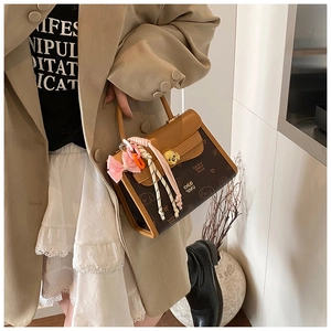 Dettaglio della borsa vintage in pelle marrone con stampe di cani e ciondolo decorativo