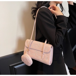 Detalle del bolso de hombro en cuero rosa con relieve de cachorros y mini monedero redondo