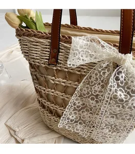 Détail du sac cabas en paille tissée avec un nœud en dentelle et une anse en cuir