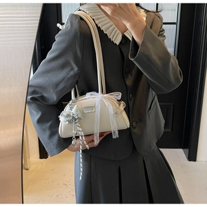 Détail du sac bowling blanc crème avec des rubans en dentelle et un pendentif nœud