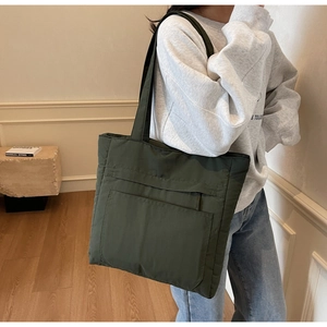 Close-up of olive green nylon tote bag with functional front zipper pocket details