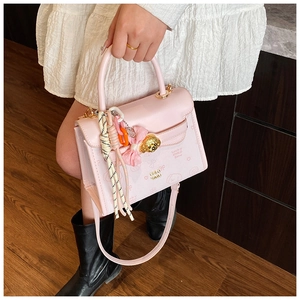 Vista dettagliata della borsa in pelle rosa con ciondolo a cane dorato e accessori pendenti