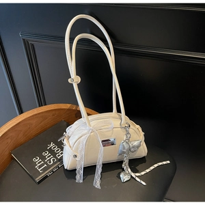 Détail du sac à bandoulière blanc cassé avec nœud en dentelle et pendentif papillon argenté