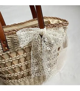 Gros plan du sac fourre-tout en paille avec poignées en cuir et nœud en dentelle