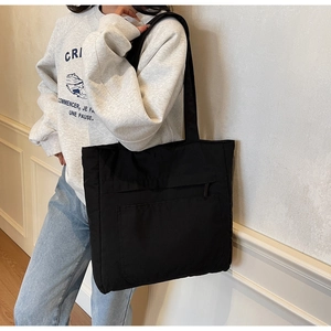 Detail of black large capacity tote bag featuring a practical front zipper pocket