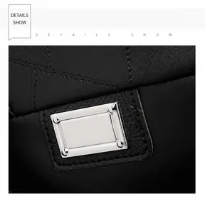Close-up of black textured faux leather with a rectangular silver metal ornament and stitching