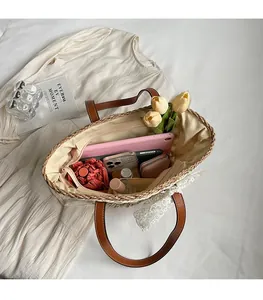 Grand sac cabas en paille avec anses en cuir marron montrant un intérieur spacieux