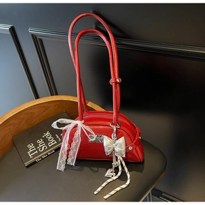 Détail du sac rouge avec ruban en dentelle blanche et pendentifs nœuds argentés