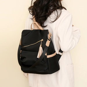 Detail of stylish anti-theft nylon backpack for women with fringe charm on back of model