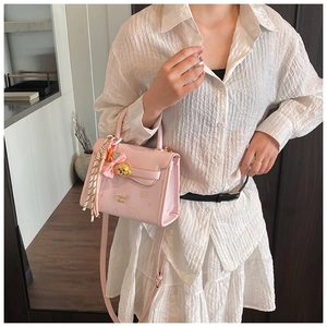 Dettaglio borsa rosa chiaro con chiusura a cane in metallo e decoro foulard a righe