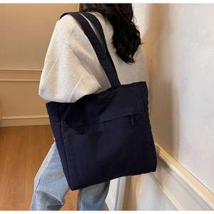 Detail of dark blue tote bag showing the front zipper pocket and durable nylon material