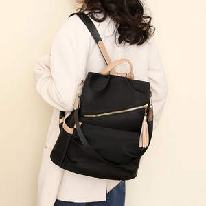Close-up of black anti-theft nylon backpack with elegant tassel and gold zipper detail