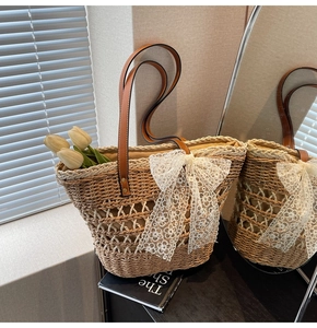 Détail du sac cabas en paille avec nœud en dentelle blanche et anses en cuir brun