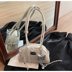 Détail du sac hobo blanc crème avec nœud en dentelle et pendentif cœur sur de la soie