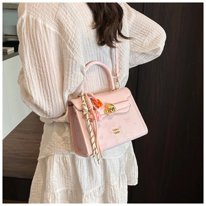 Dettaglio borsa in pelle rosa con chiusura a forma di orsetto e sciarpa floreale