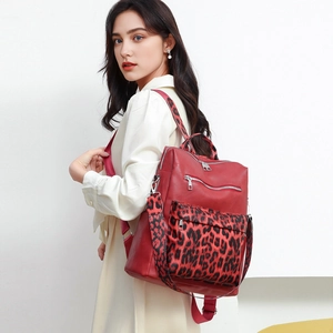 Detail of red leopard print backpack with silver metal zippers worn by model