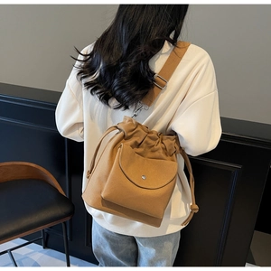 Dettaglio di una borsa a secchiello in tela marrone con tracolla regolabile e tasca a clip