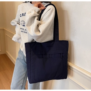 Detail view of large dark blue tote bag with front zipper pocket and long shoulder straps