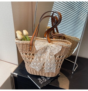 Vue détaillée du sac en paille avec nœud en dentelle blanche et anses en cuir brun