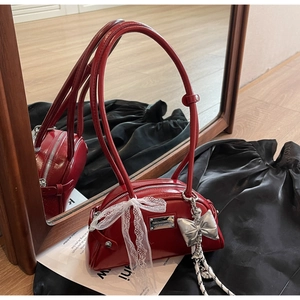 Détail du sac à main en cuir verni rouge avec nœuds en dentelle et fermeture éclair en métal
