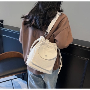 Dettaglio della borsa a secchiello in tela beige con tracolla ampia regolabile