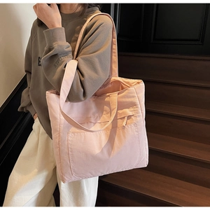 Detail of light pink quilted tote bag with wide straps and large front pocket