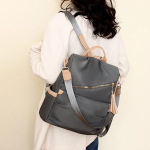 Deep grey anti-theft nylon backpack with tassel and khaki PU straps shown on model