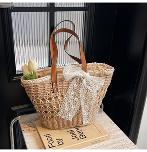Détail du sac cabas en paille bohème avec nœud en dentelle blanche et anses en cuir
