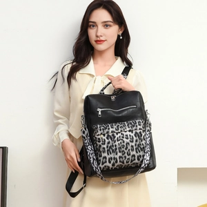 Detail view of stylish leather leopard print backpack with silver zippers and wide straps