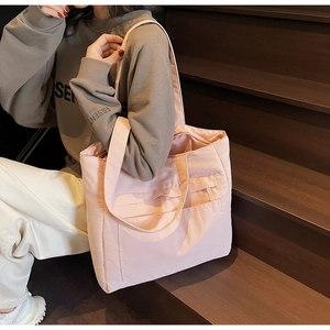Detail of a pink large capacity tote bag with front pocket carried on one shoulder