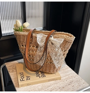 Détail du sac cabas en paille tissé main avec anses en cuir et nœud en dentelle blanche