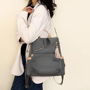 Detail of dark grey nylon anti-theft backpack with gold zippers and brown leather trim
