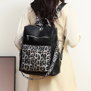 Close-up of black PU leather backpack with leopard print details and metal zippers