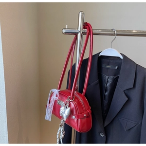Détail du sac à bandoulière rouge brillant avec nœud argenté et ruban en dentelle