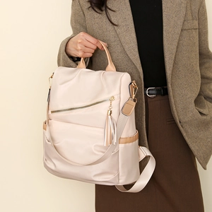 Detail of light beige nylon anti-theft backpack featuring stylish leather tassels