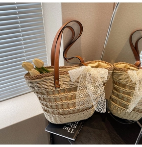 Détail du sac cabas en paille tissé main avec nœud en dentelle blanche et anses en cuir