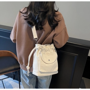 Dettaglio borsa a secchiello in tela beige con coulisse e tasca frontale a patta