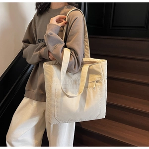 Minimalist beige tote bag showing large capacity pocket on wooden stairs