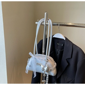 Détail du sac à main bleu clair avec nœud en dentelle et pendentif cœur en métal