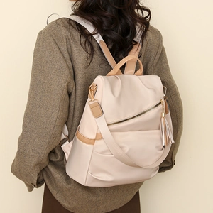 Detail of waterproof nylon backpack with golden zipper and stylish tassel accessory