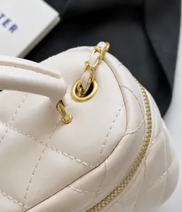 Detail of cream quilted leather bag with gold hardware, zipper and chain strap