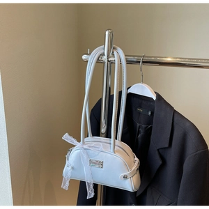 Détail d'un sac à main brillant bleu clair avec un nœud en dentelle blanche sur un cintre