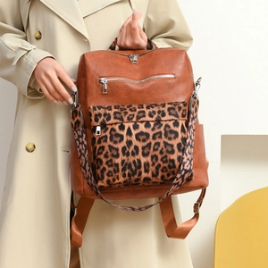 Detail of leopard print suede texture and silver metal zippers on brown leather backpack