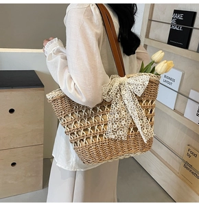 Sac cabas en paille avec nœud en dentelle blanche et anses en cuir sur mannequin