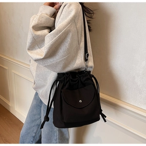 Dettaglio di una borsa a secchiello nera con coulisse, tasca a patta e trama in tela